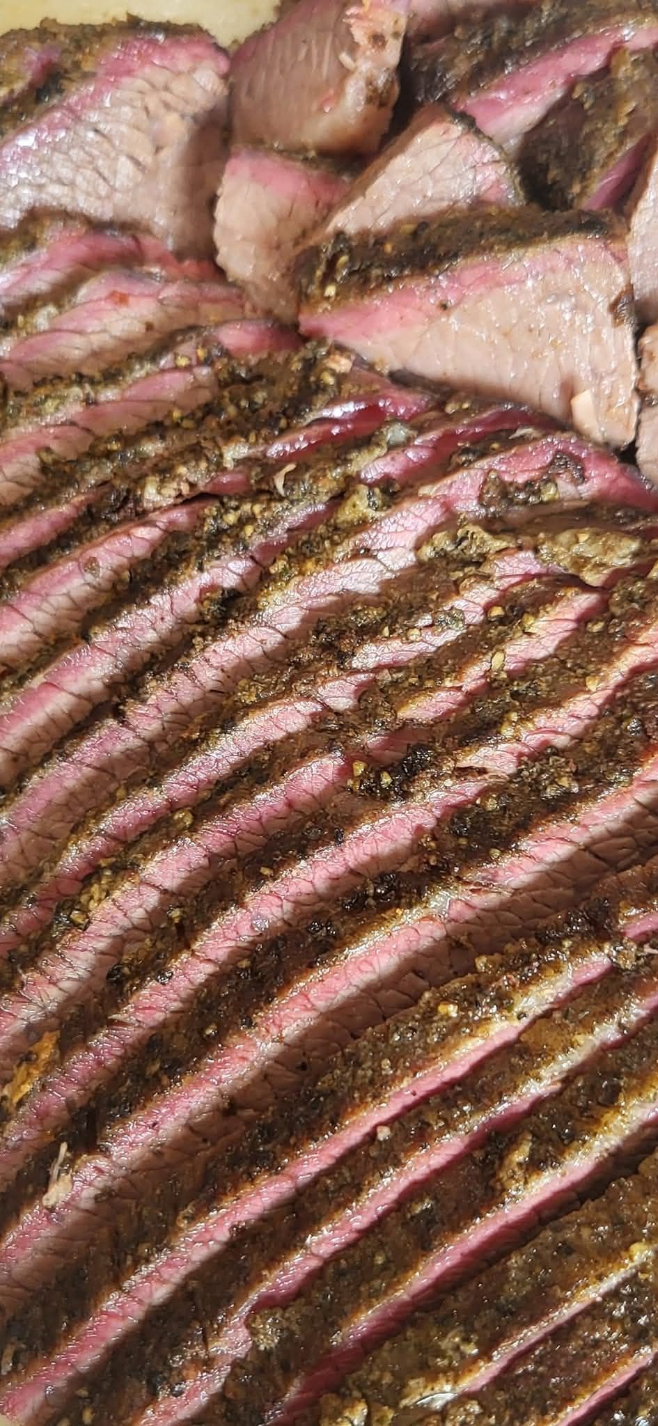 Sliced brisket with a visible crust and seasoning. Pink meat is visible between the slices.