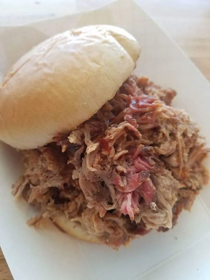 Pulled pork sandwich on a bun in a paper tray.