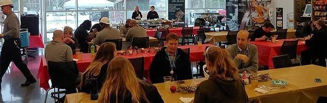 People sitting and standing at tables in a large room, likely an event or meeting.