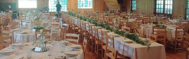 Long tables with simple decorations set for a banquet in a wood-paneled room.