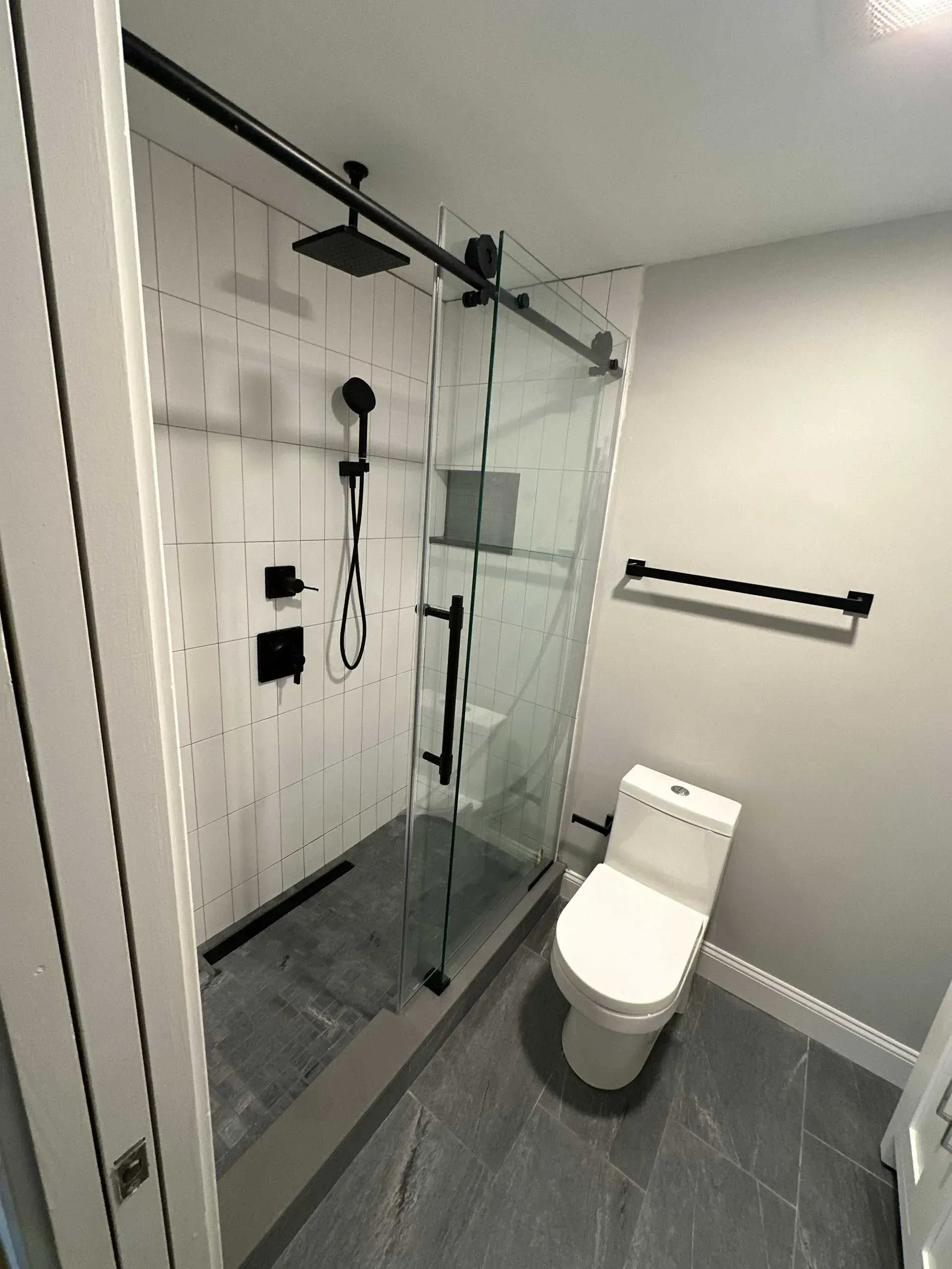 Modern bathroom with a glass shower, black fixtures, and a white toilet.