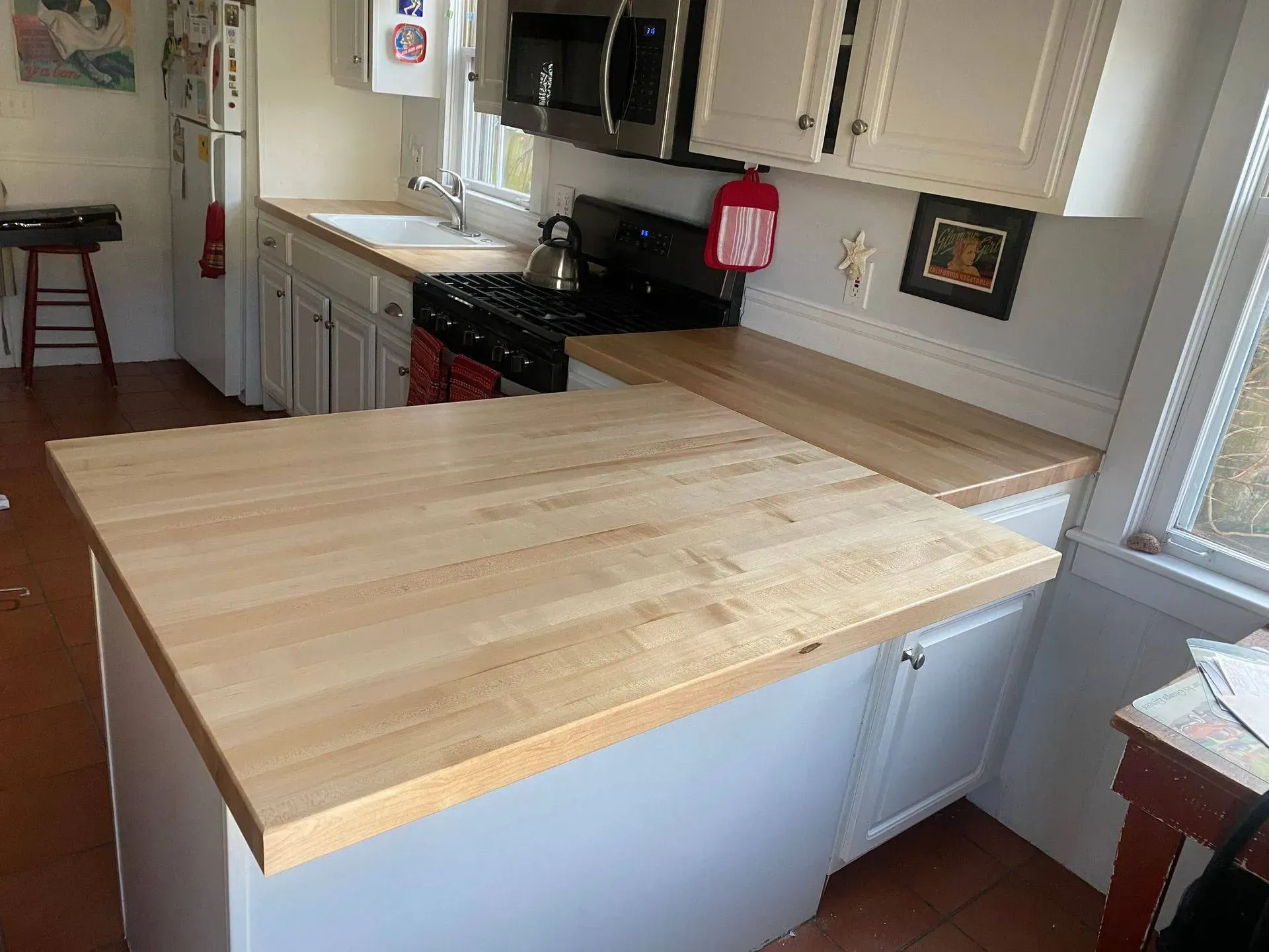 Small kitchen with white cabinets, wood countertops, and a stove.