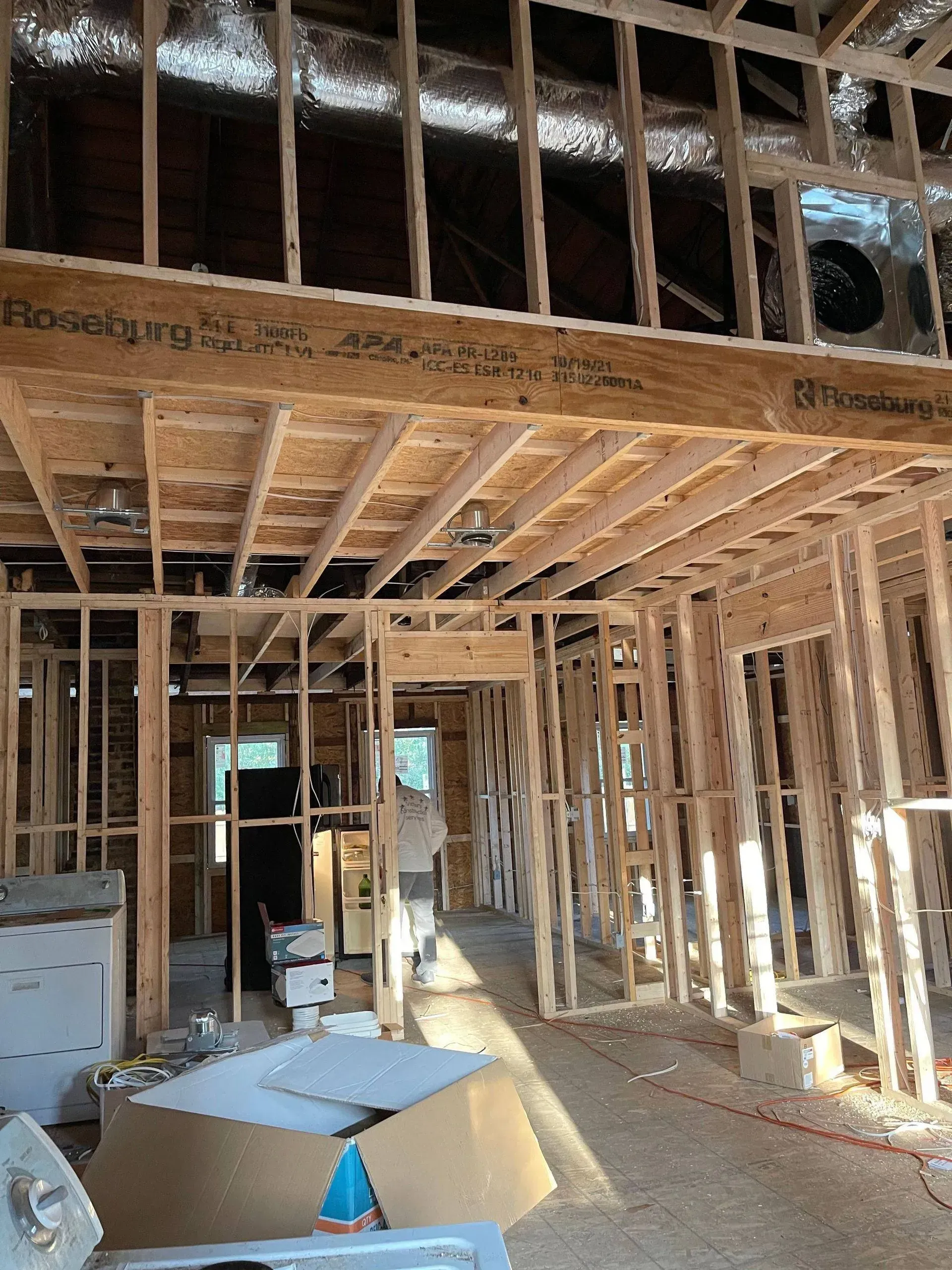 Interior view of a building under construction, showing wooden framing and exposed ceiling beams.