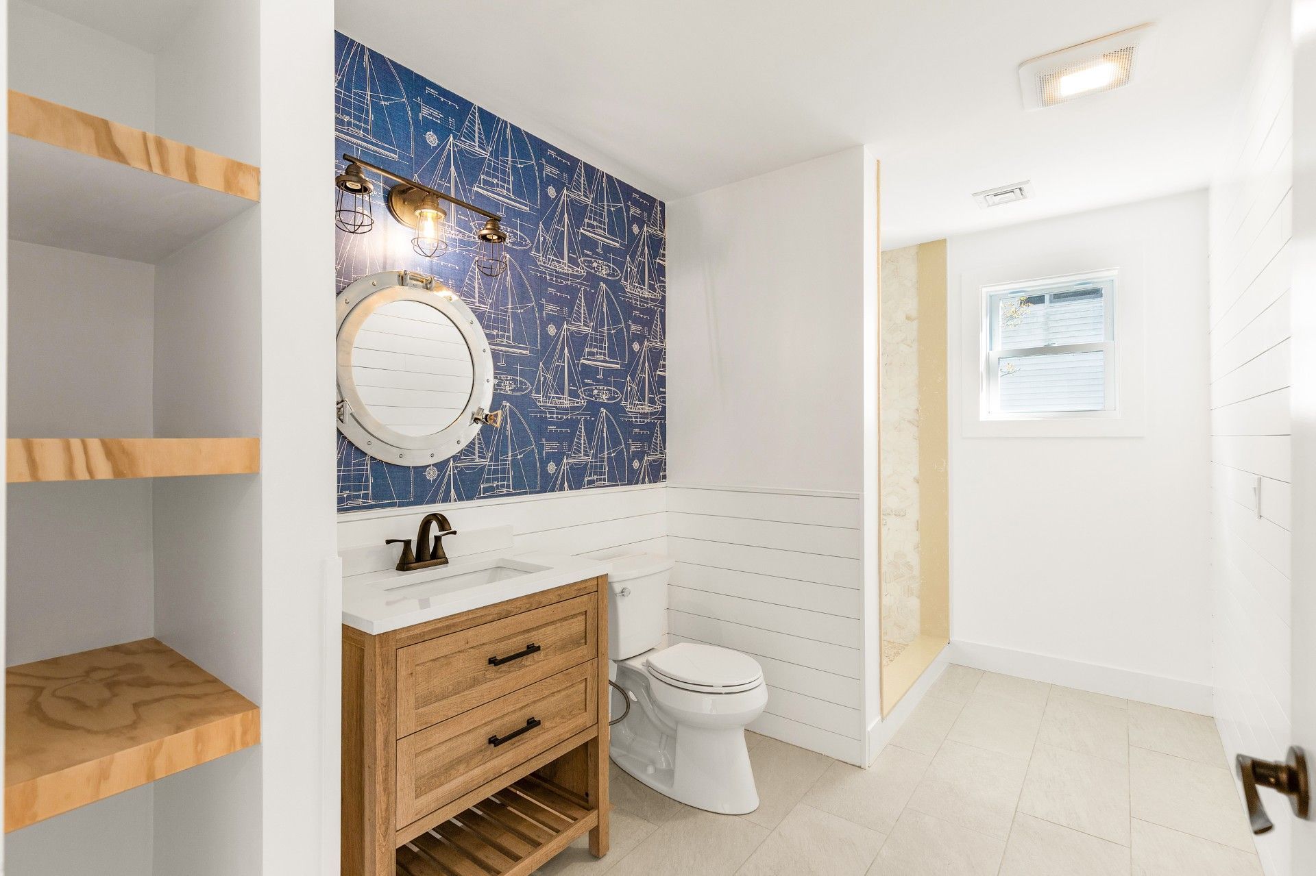 Bathroom with blue patterned accent wall, wooden vanity, and tiled floors.