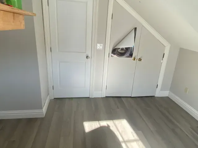 a room with hardwood floors, a closet, and a door