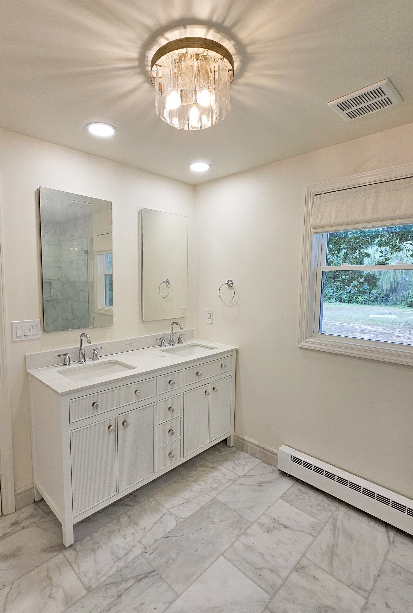 A bathroom with two sinks, a mirror, and a window.