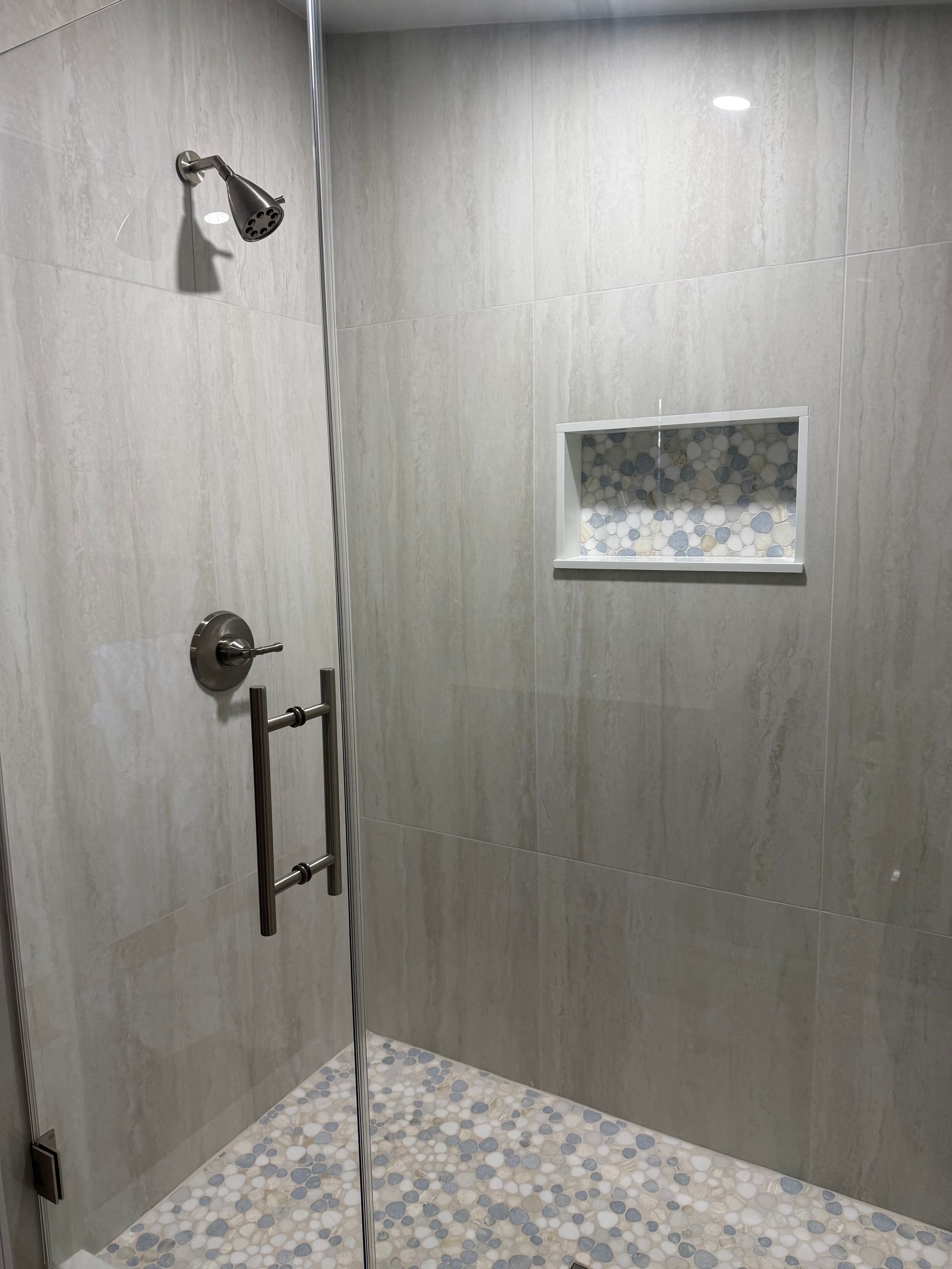 A walk in shower with a glass door and a shower head.
