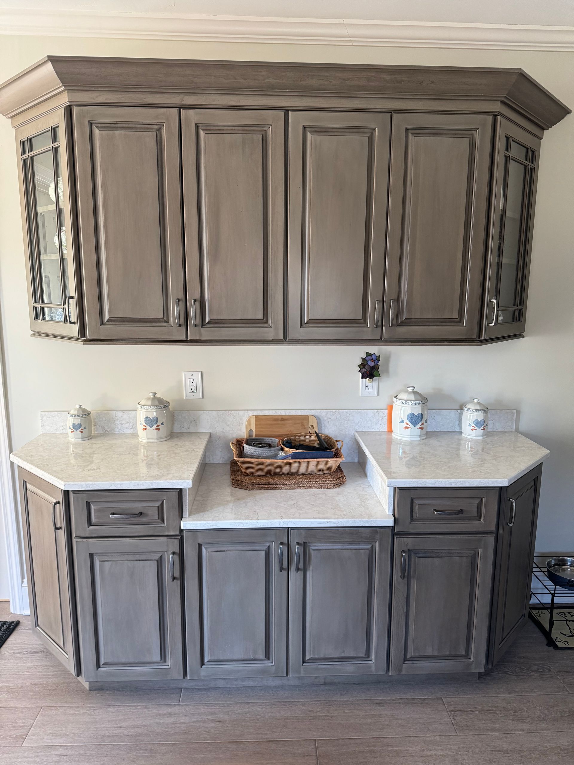 A kitchen with gray cabinets and white counter tops.