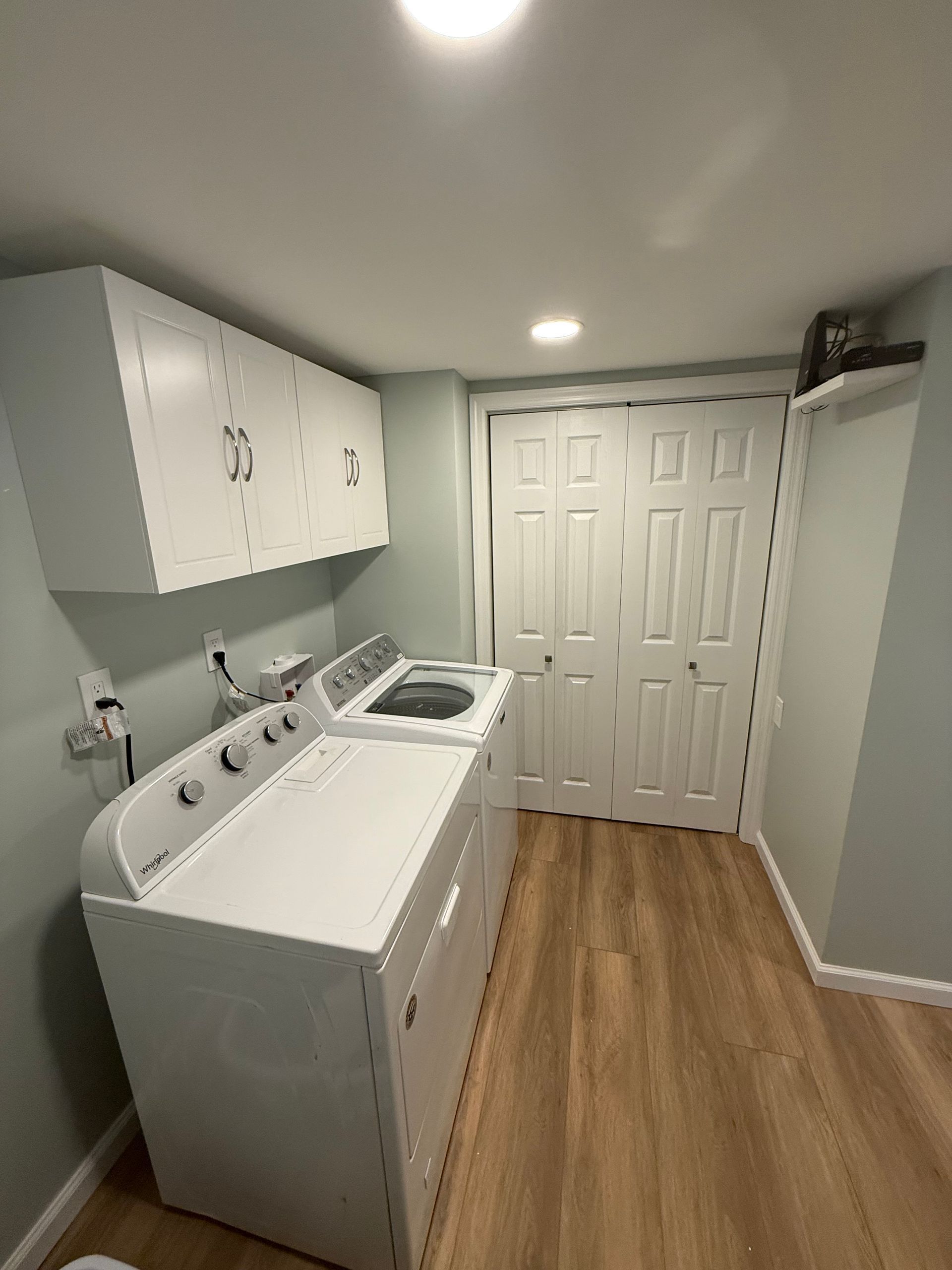 A laundry room with a washer and dryer and wooden floors.