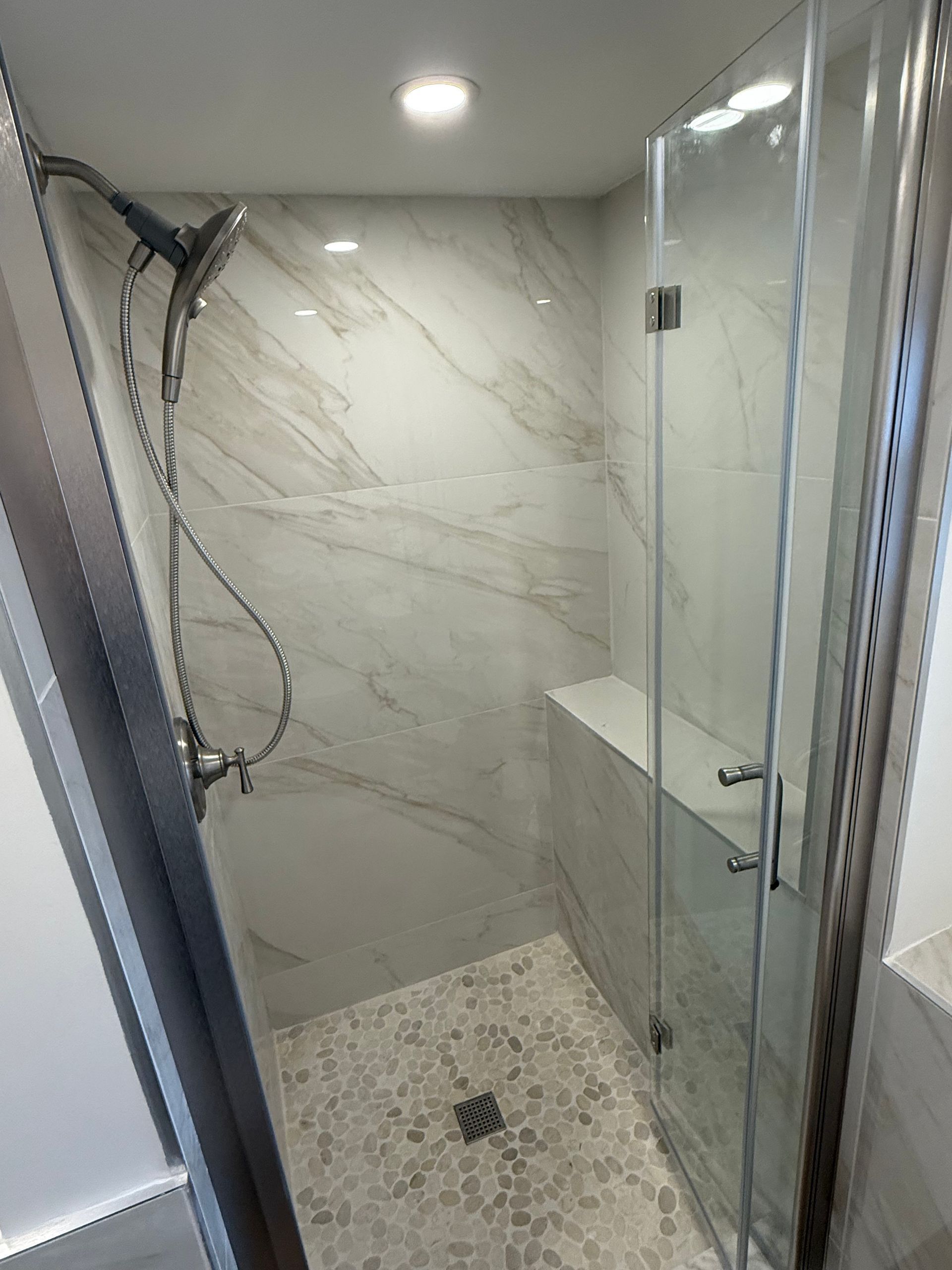 A bathroom with a walk in shower and a shower head.