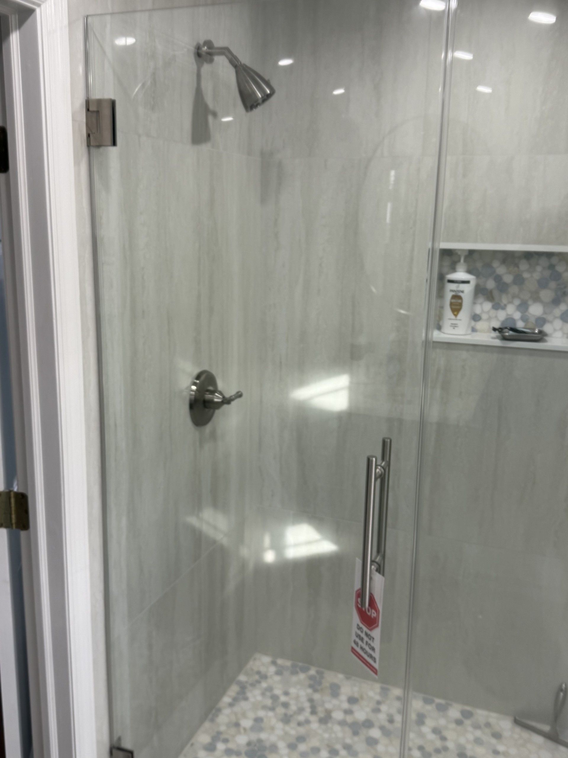A shower with a glass door and a shower head