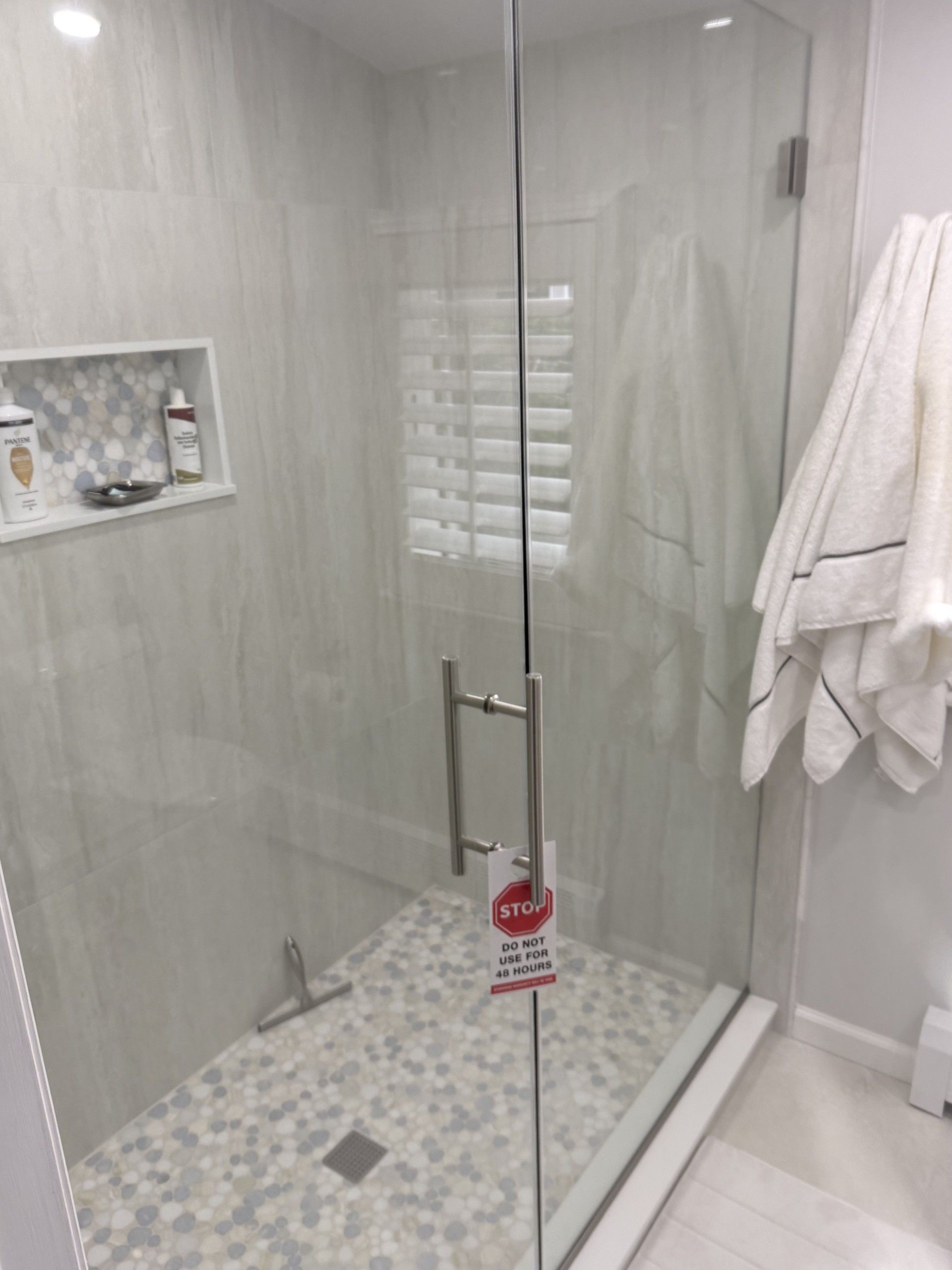 A bathroom with a walk in shower with a glass door