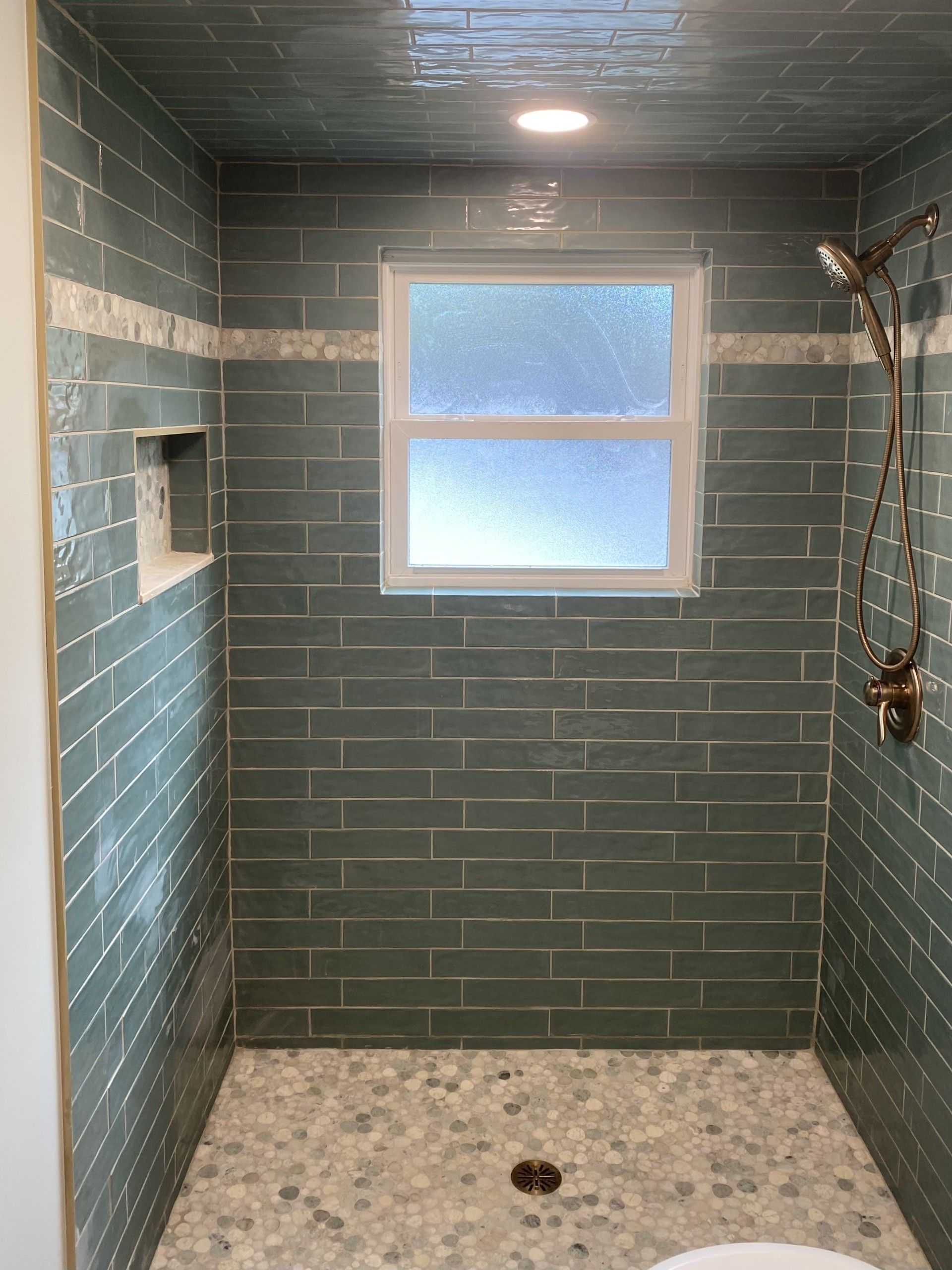 A bathroom with a walk in shower and a window.