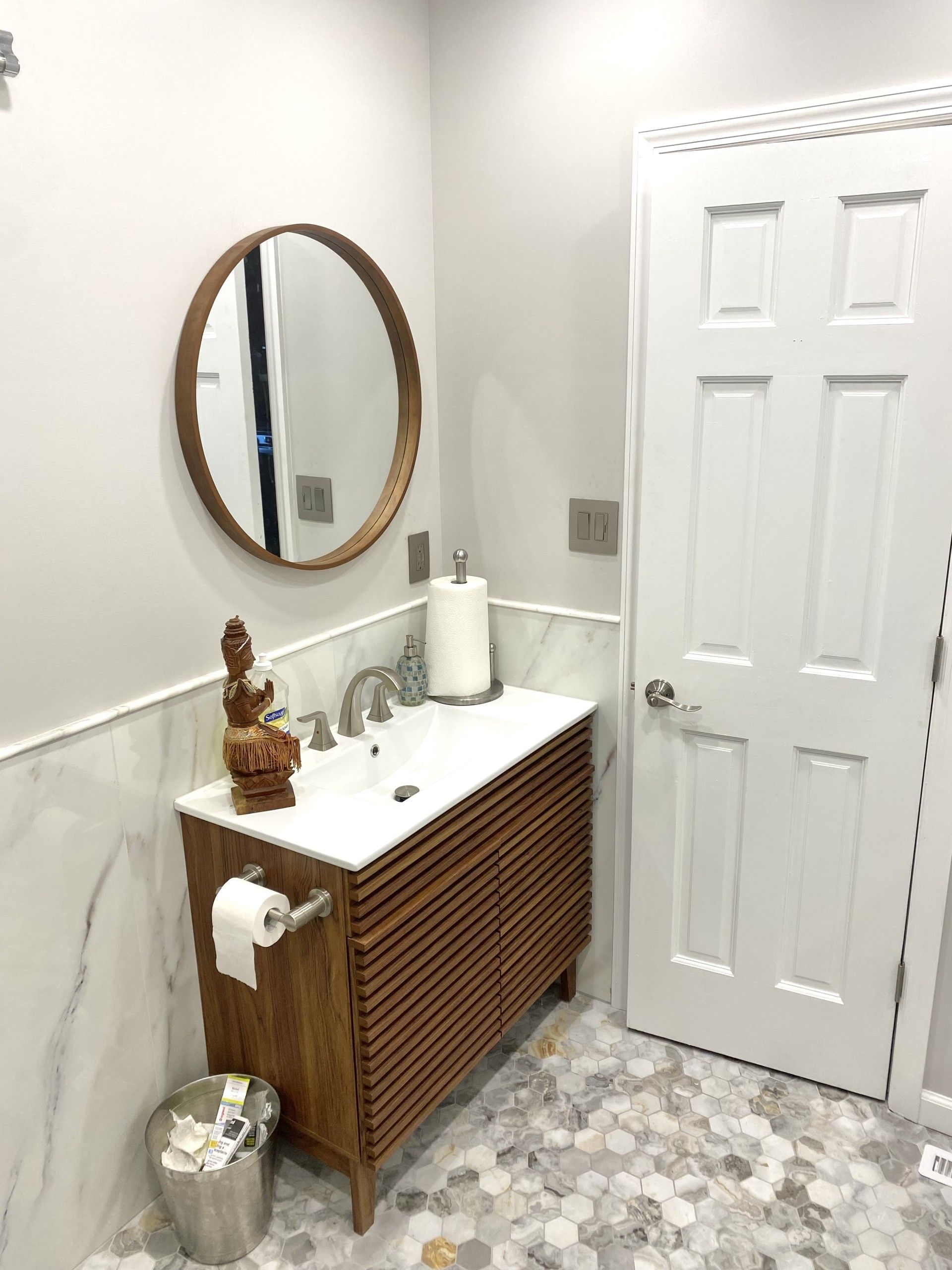 A bathroom with a sink , mirror and toilet paper.