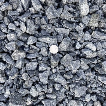 Gray crushed stone with a coin for size comparison