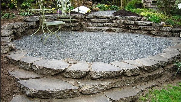 A patio with a table and chairs surrounded by rocks and gravel.