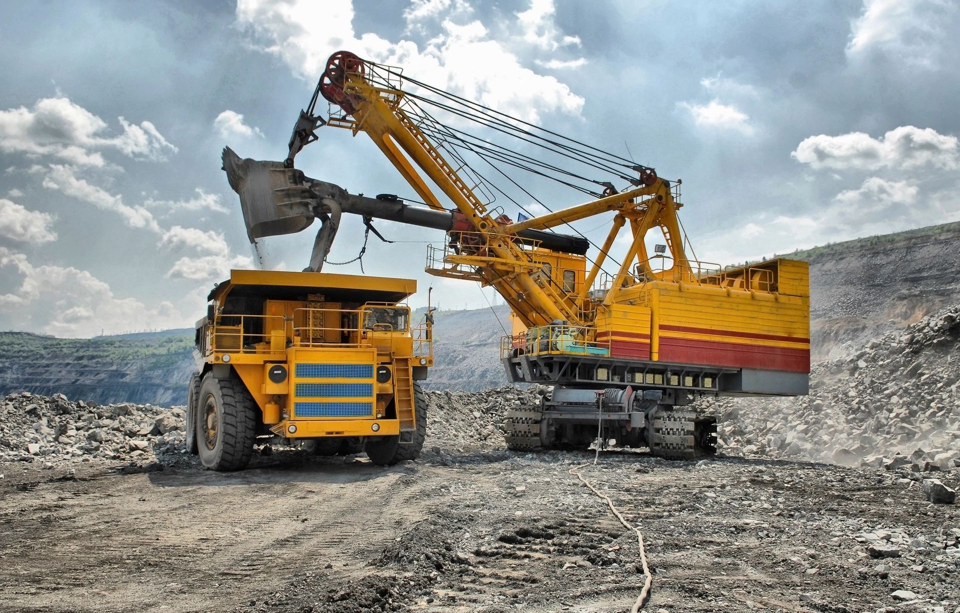A large excavator is loading a dump truck in a mine.