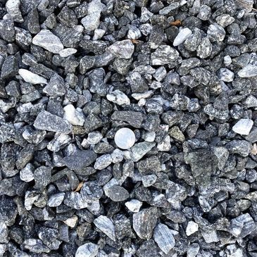 A pile of black gravel with a white rock in the middle.