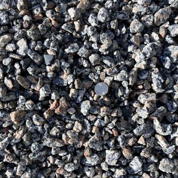 A pile of gravel with a quarter sticking out of it.