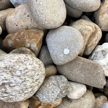 A pile of rocks with a coin sticking out of one of them.