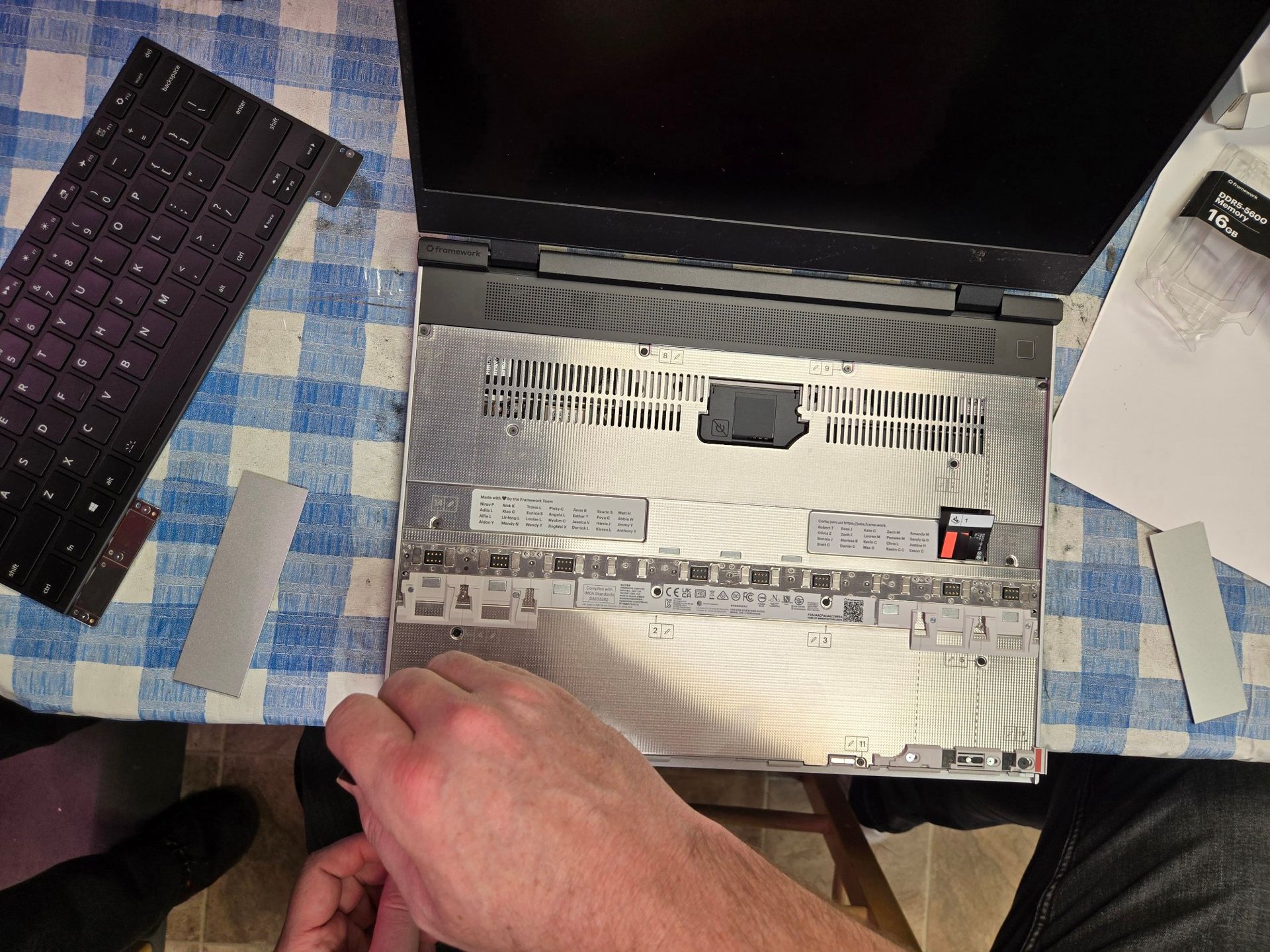 A person is taking apart a laptop computer on a table.