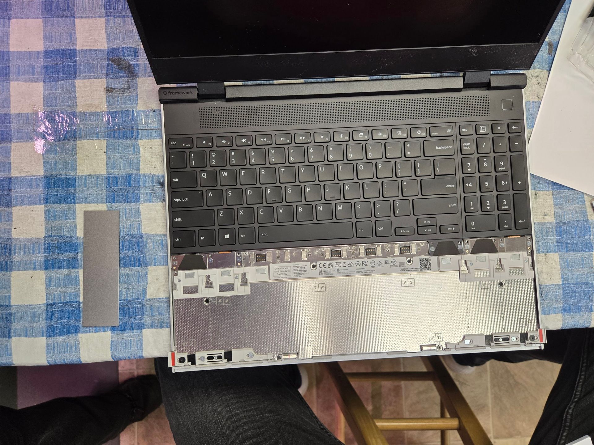 A laptop is sitting on a blue and white checkered table cloth.