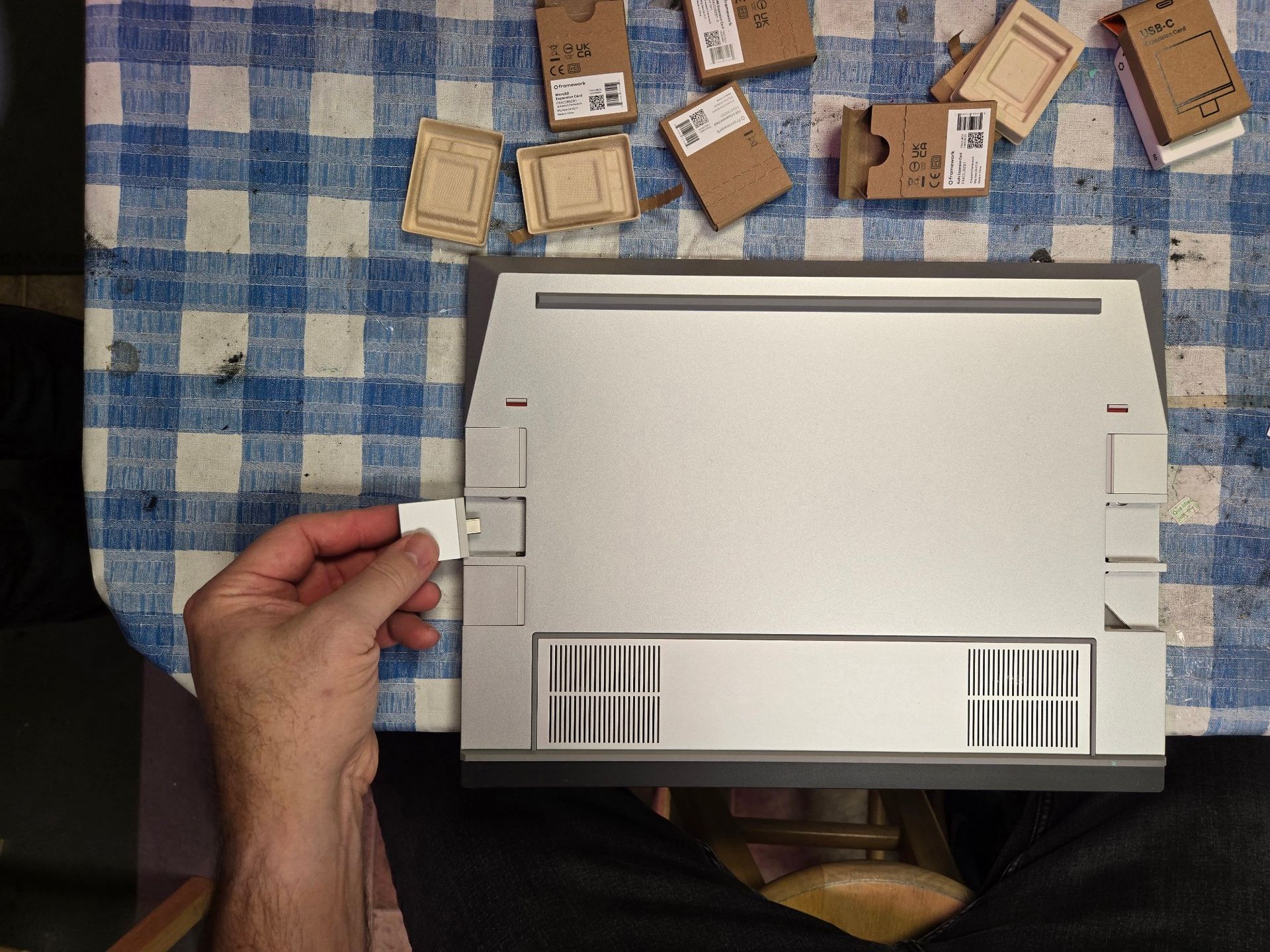 A person is holding a piece of cardboard in front of a laptop.