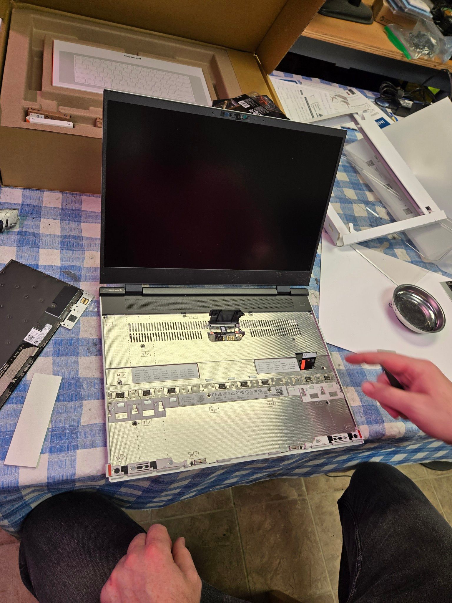 A person is taking apart a laptop computer on a table.