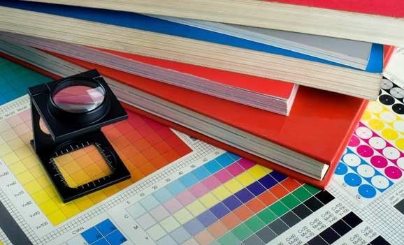 A magnifying glass is sitting on top of a stack of books.