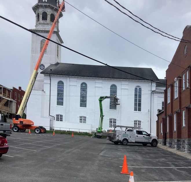 Worker in lift painting a white church