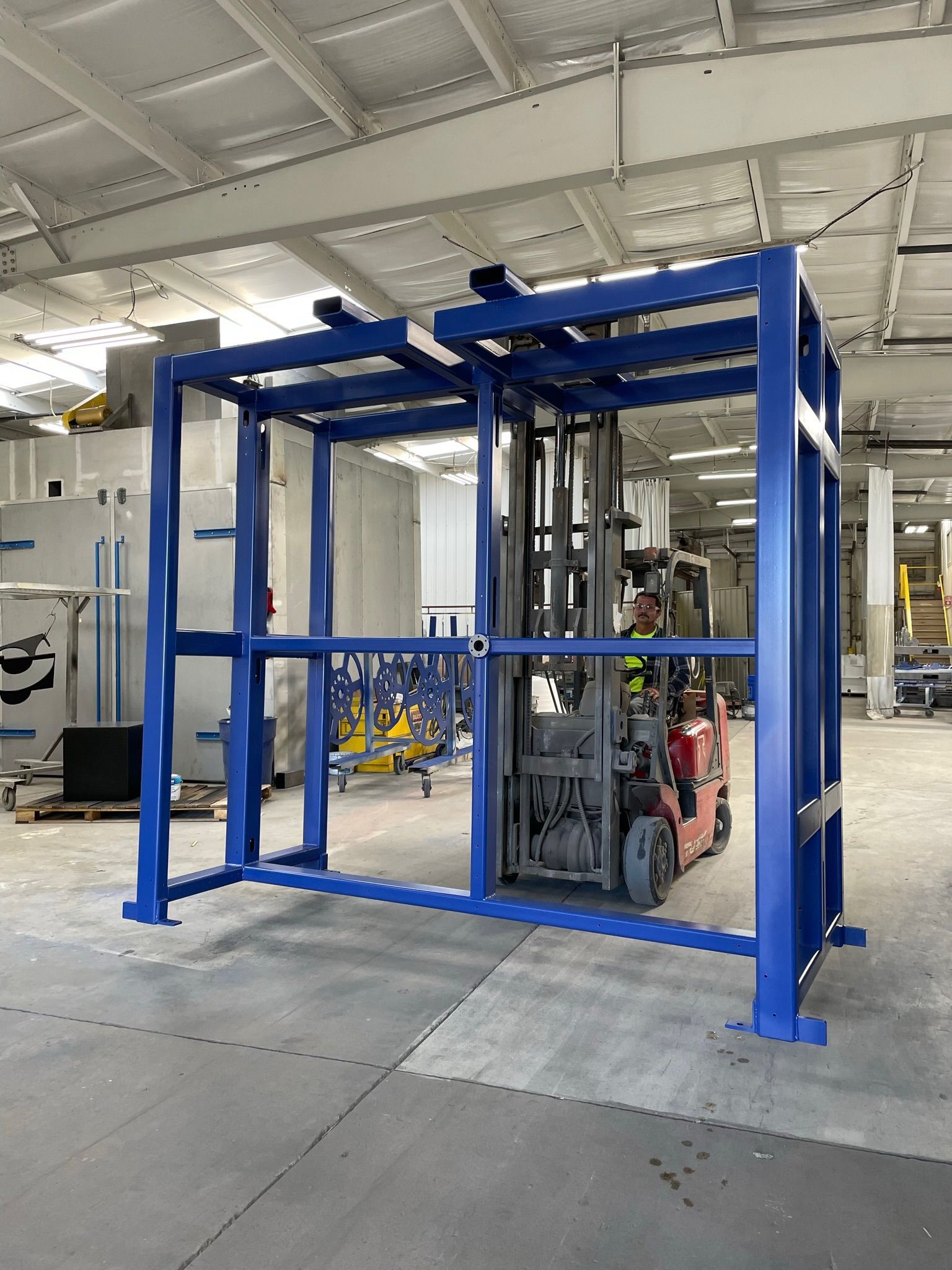 A forklift is driving through a blue frame in a warehouse.