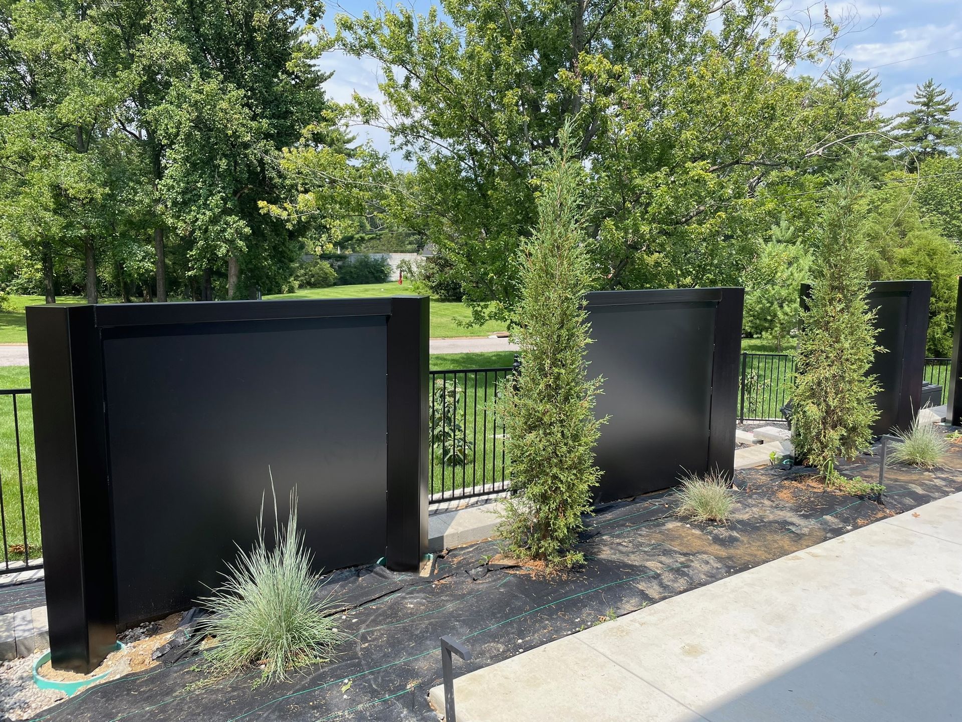 A row of black planters sitting next to a sidewalk
