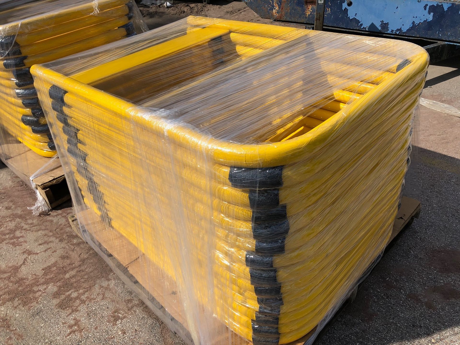 A stack of yellow scaffolding is wrapped in plastic and sitting on a wooden pallet
