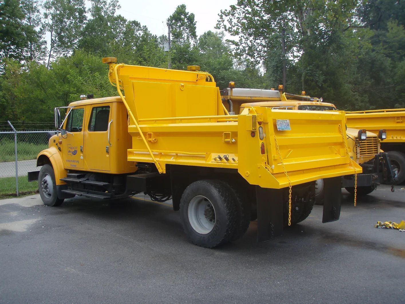 A yellow dump truck is parked on the side of the road