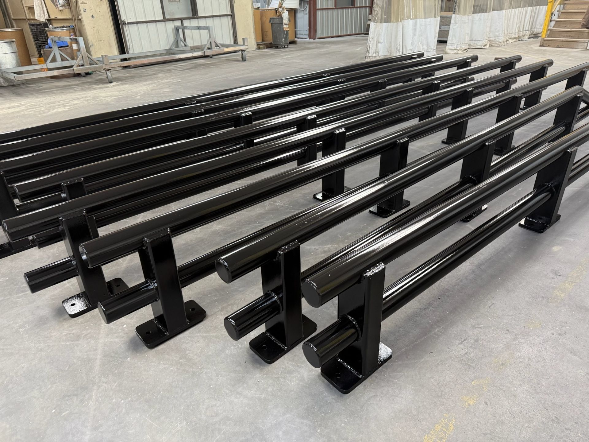 A bunch of black metal pipes are sitting on the ground.