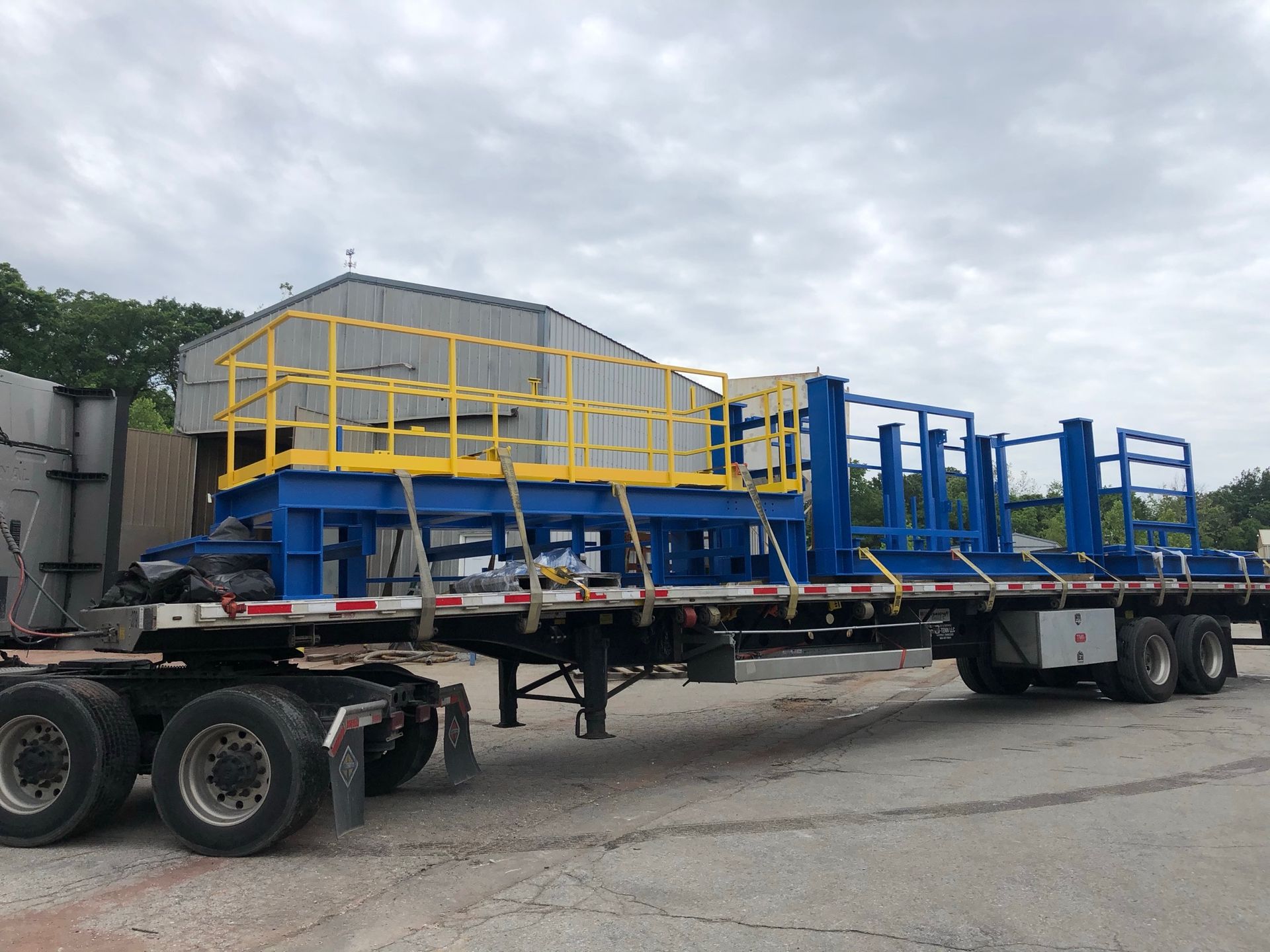 A trailer carrying a blue and yellow metal structure