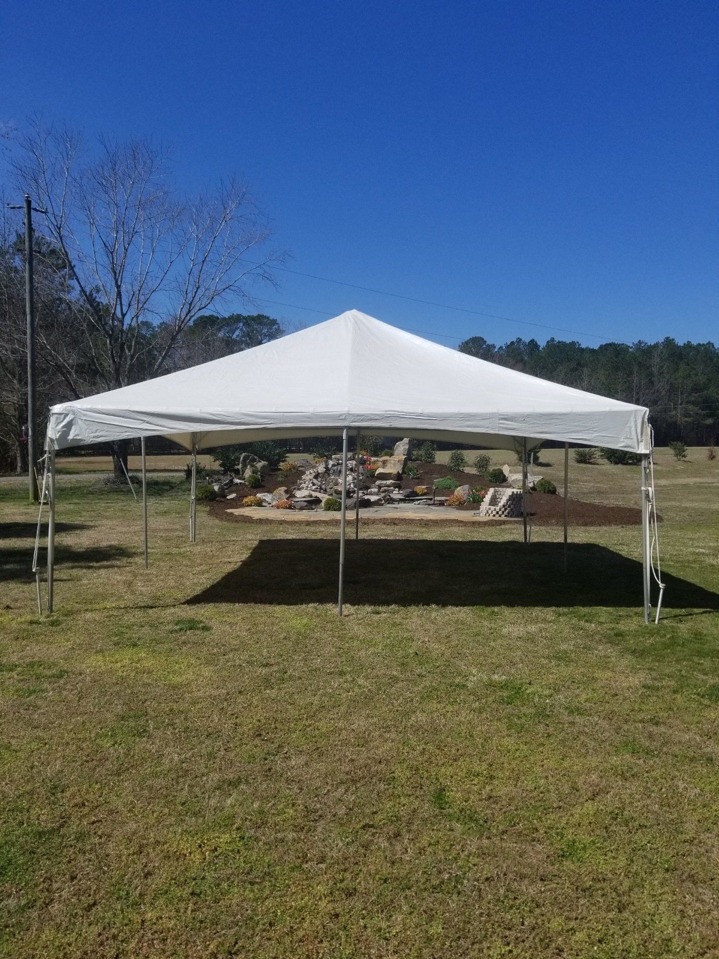 White tent set up in a grassy field with a blue sky backdrop.
