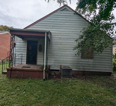 Small white house with a covered porch, front steps, and a tree in the yard