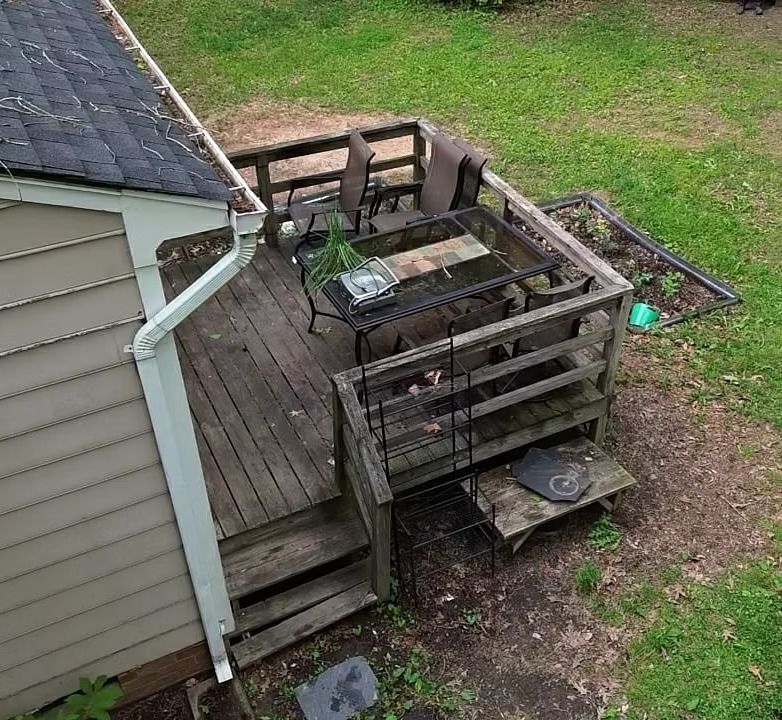 Wooden deck beside a house, with railing, steps, and a small round table on a grassy yard
