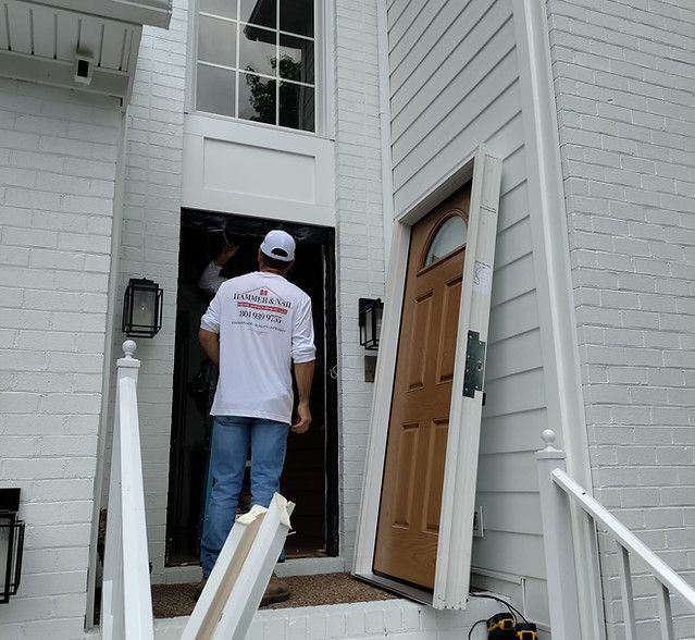 Worker entering a white house through the front door with a removed door leaning nearby