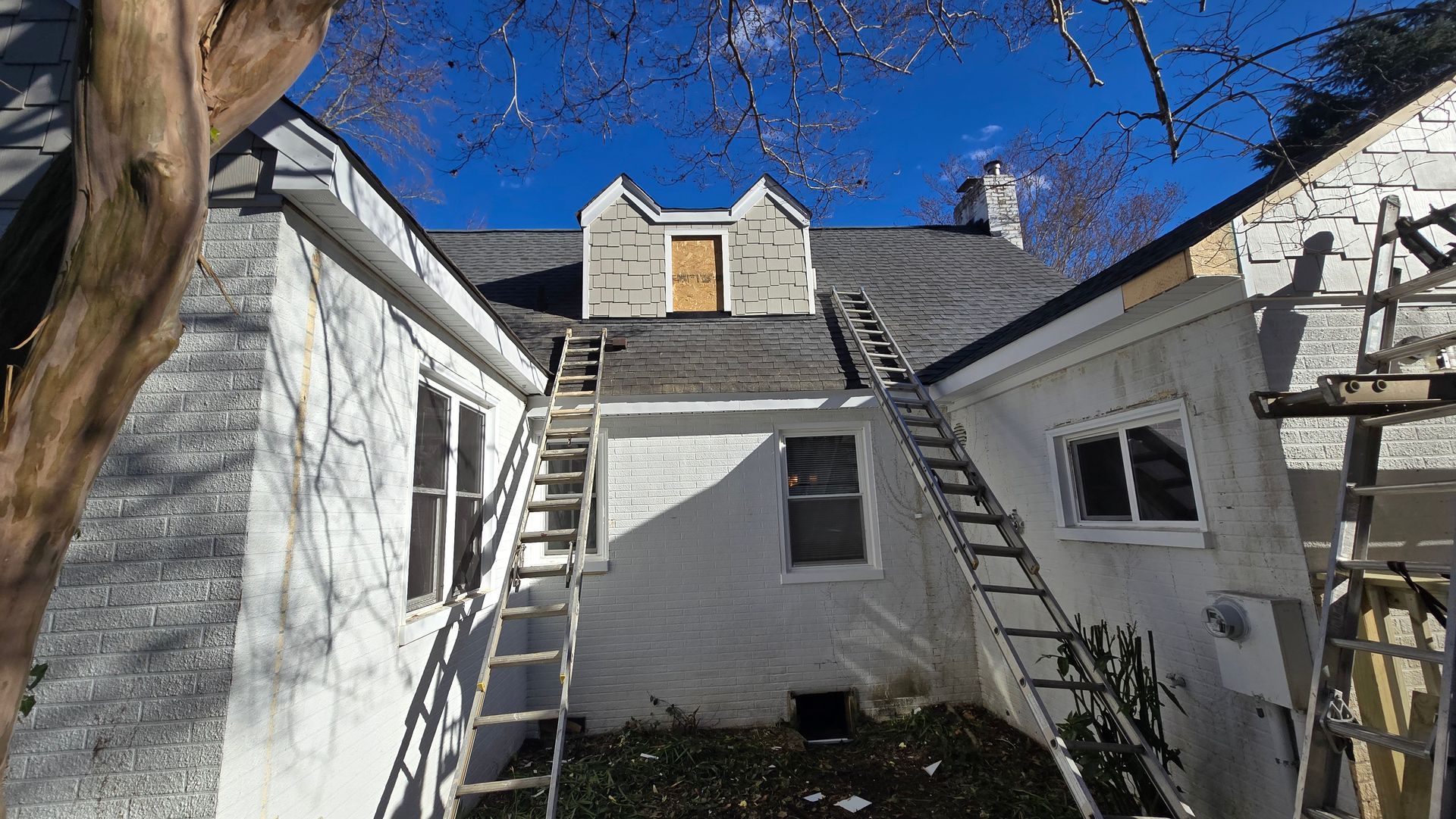 White stucco courtyard with exterior staircases leading to a small upper doorway under a blue sky