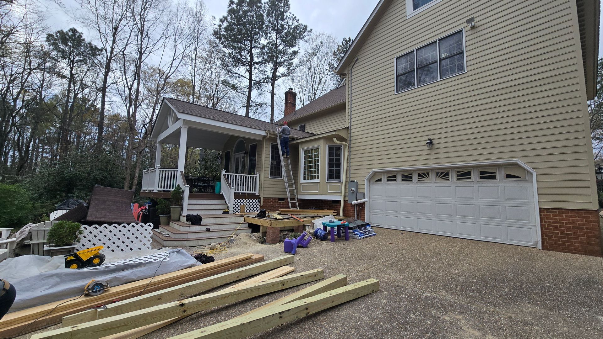 House exterior with workers, lumber, and construction materials in the front yard