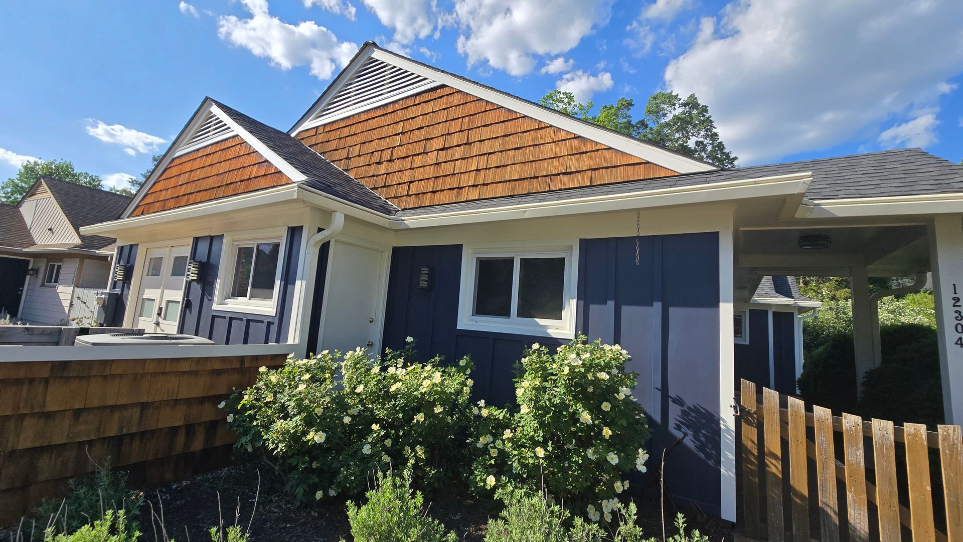 Single-story house with white trim, orange tiled roof, and a front garden under a blue sky.