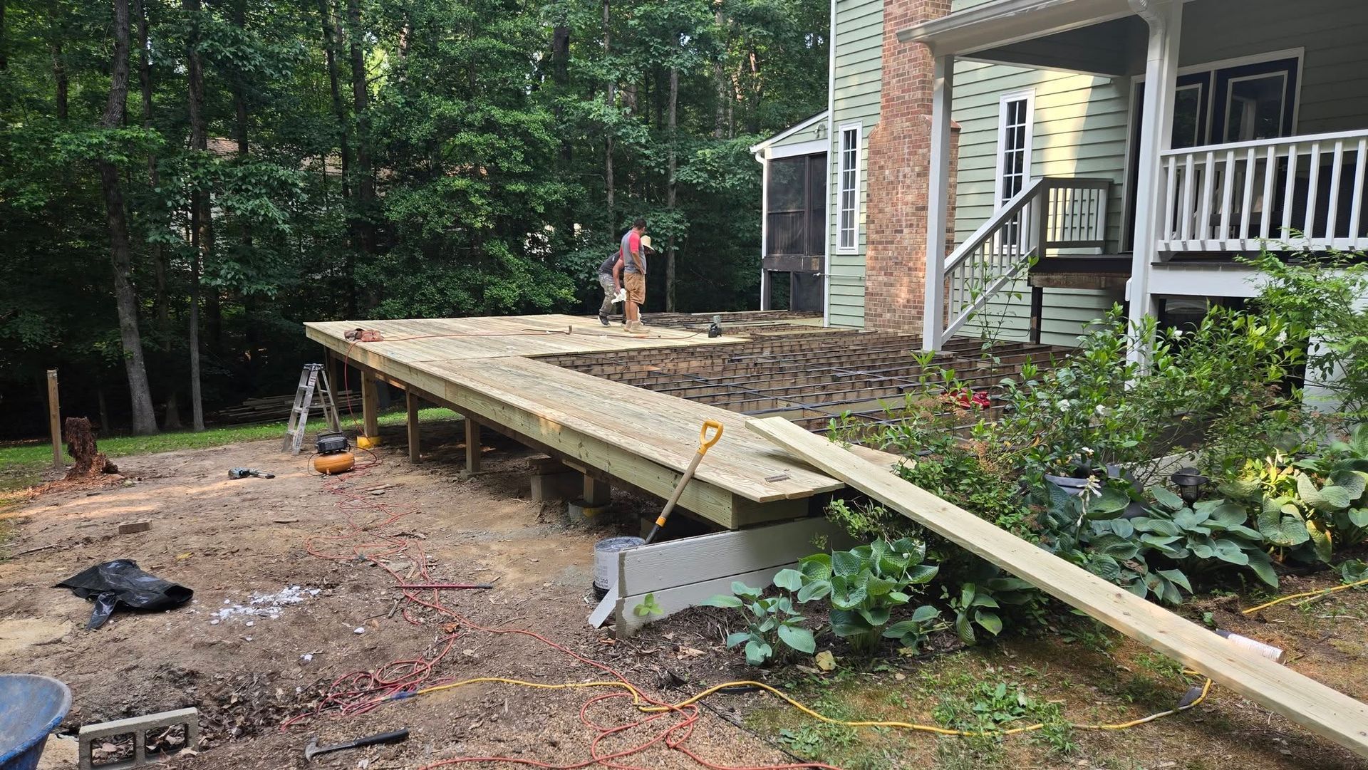 Long wooden ramp under construction beside a house, with a person working at the far end.