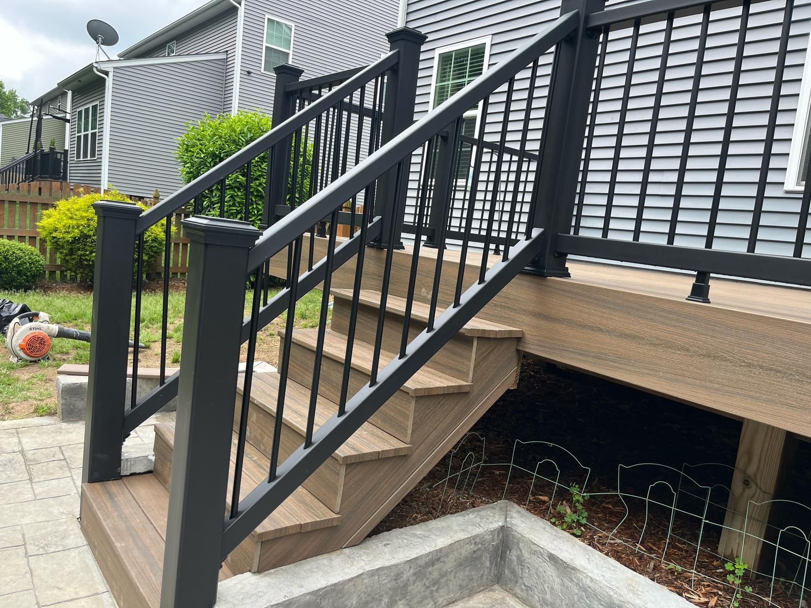 Black metal railing and stairs leading to a raised porch on a house exterior.