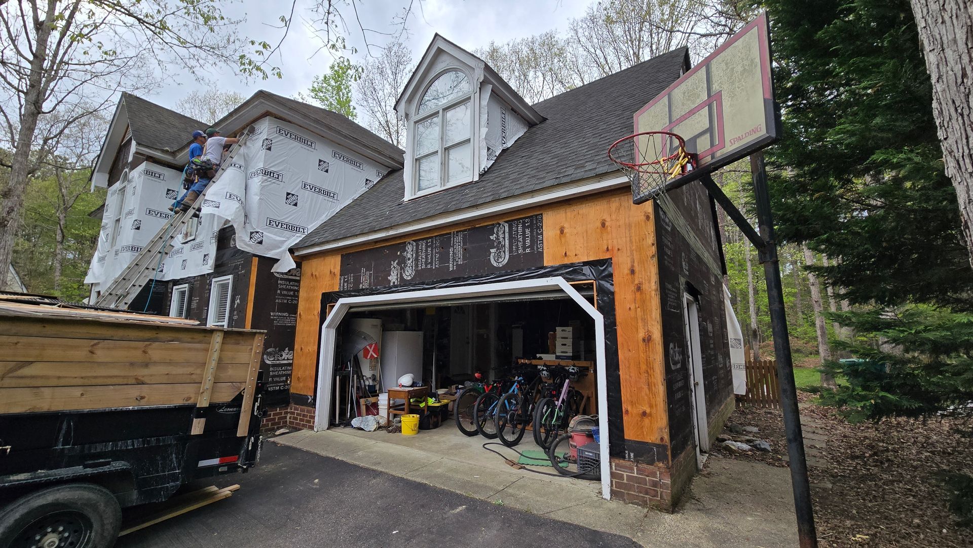 Detached garage with open door, orange siding, bicycles inside, and a basketball hoop on the side.