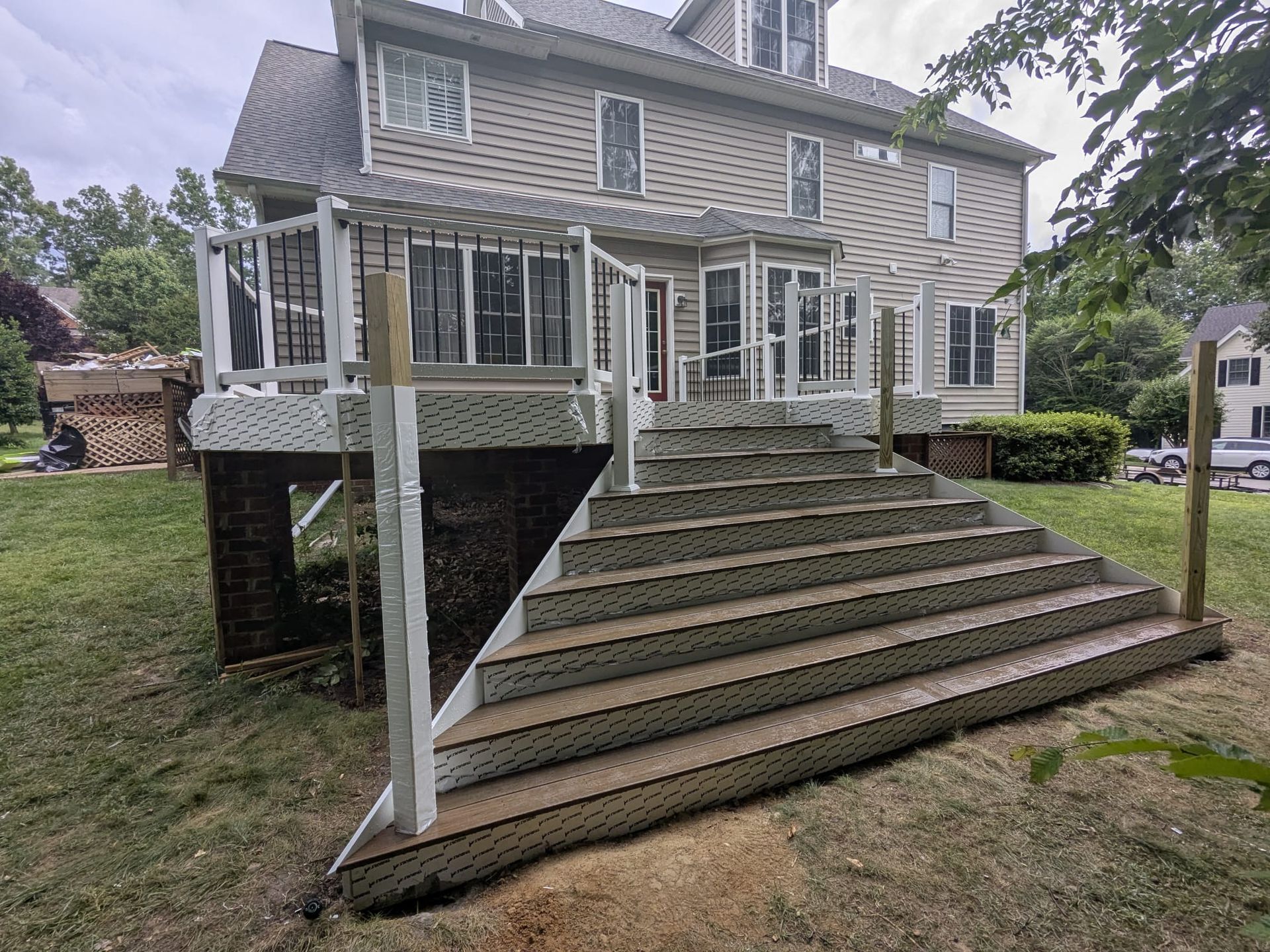 House with large wooden exterior stairs and white railings on a grassy yard
