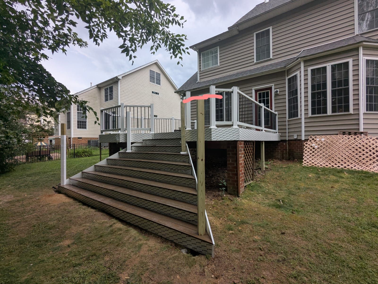 Wooden porch ramp with stairs beside a house, leading to a raised deck in a grassy yard.