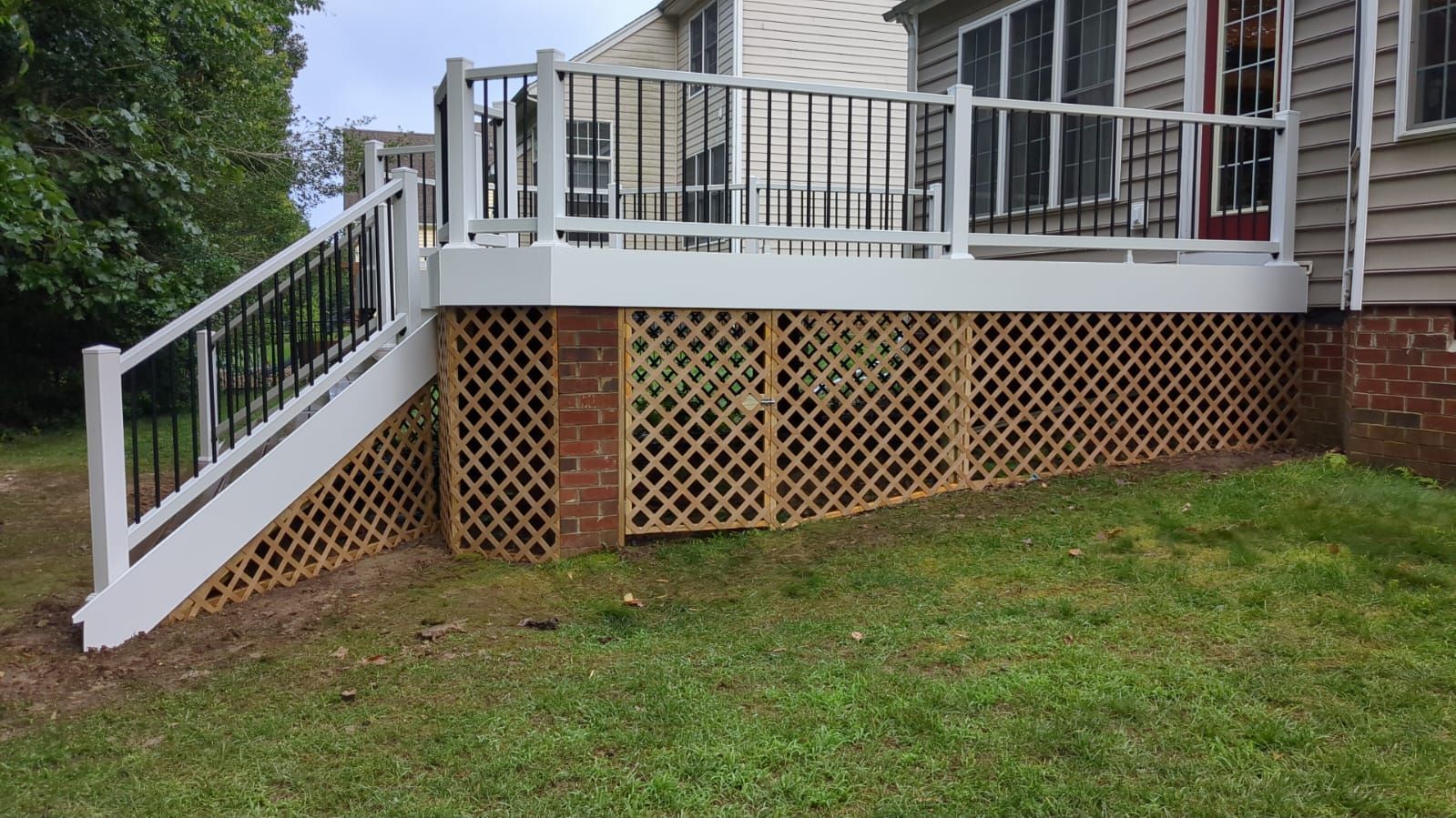 Back deck with white railings and lattice skirting over a grassy yard