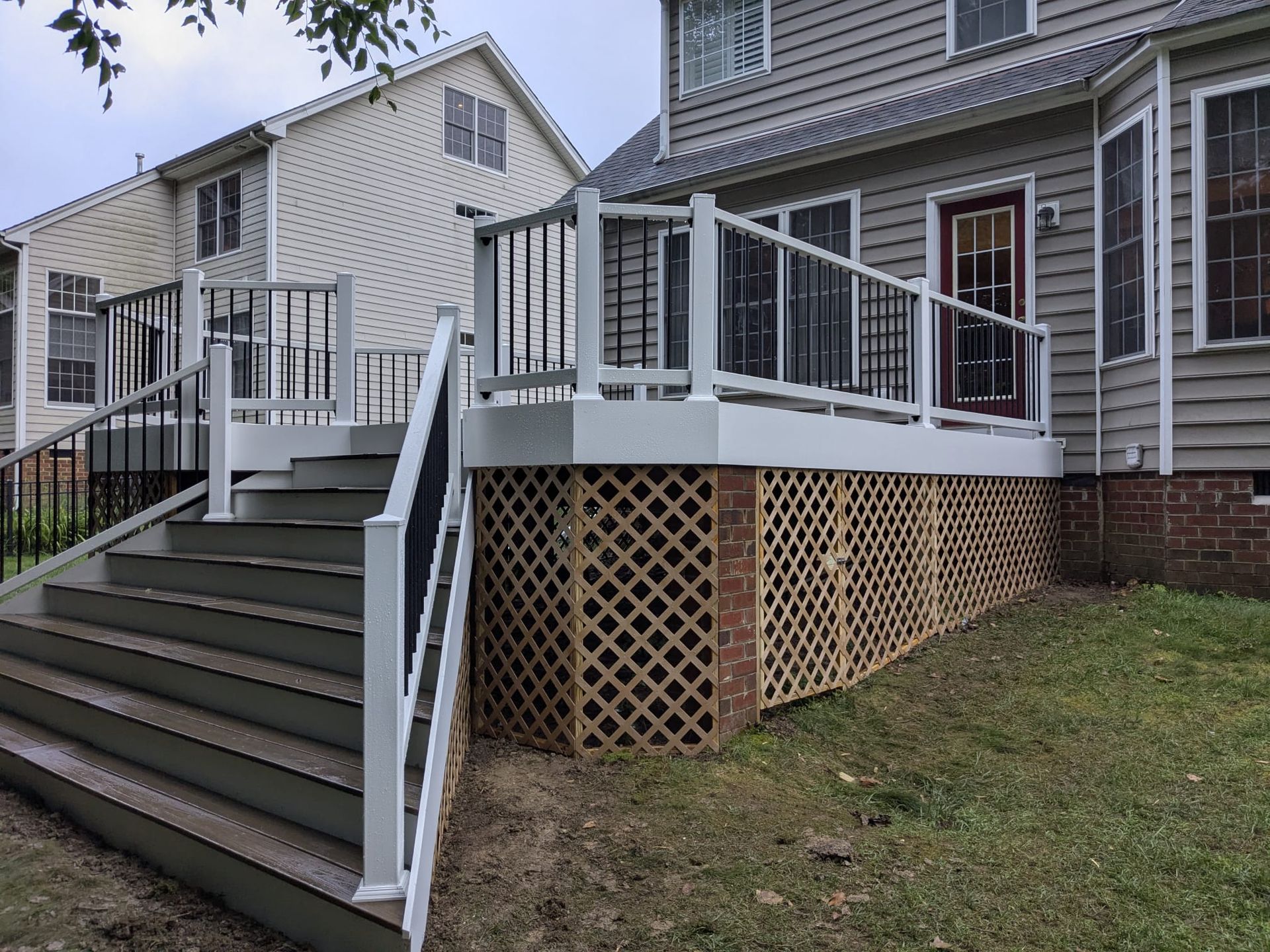 Apartment building stairs and ramp with white railings leading to a raised wooden deck and lattice skirting